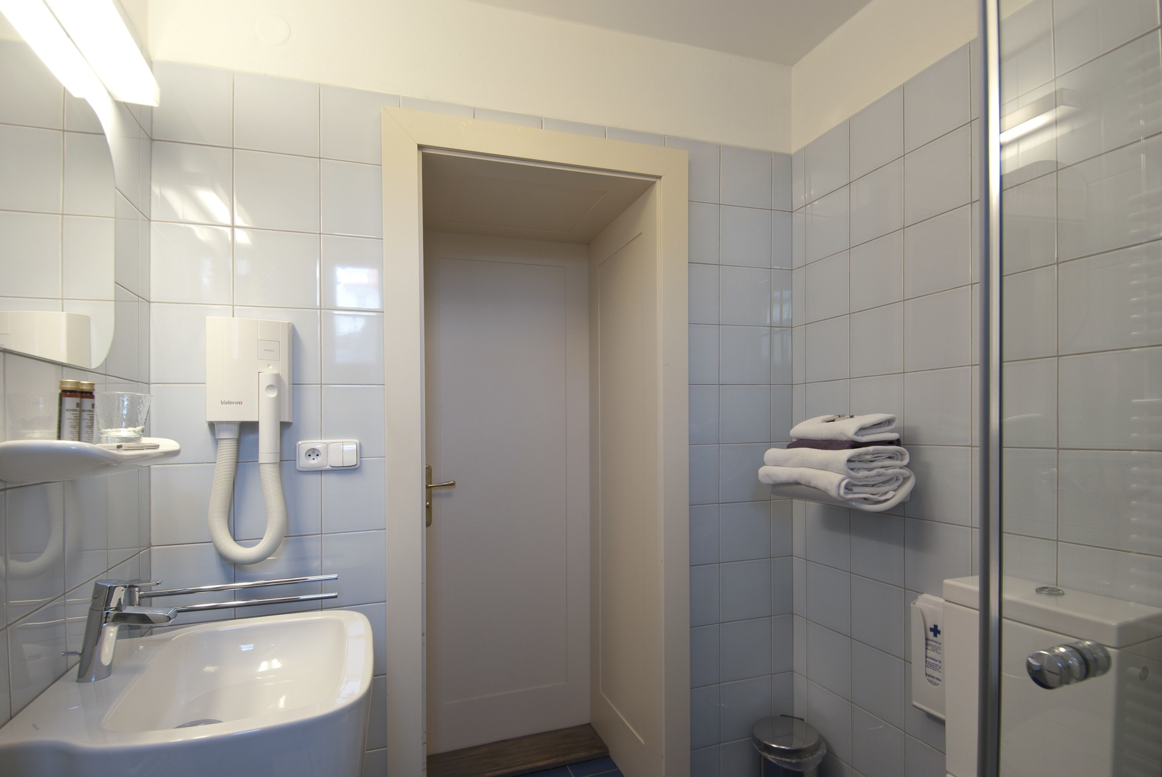 Un baño con lavamanos, espejo, toallero y retrete.