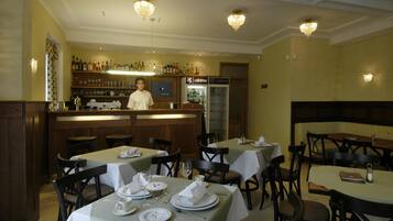 A restaurant with tables set for dining, a bar area with a bartender, and a refrigerator labeled 'cafe'.