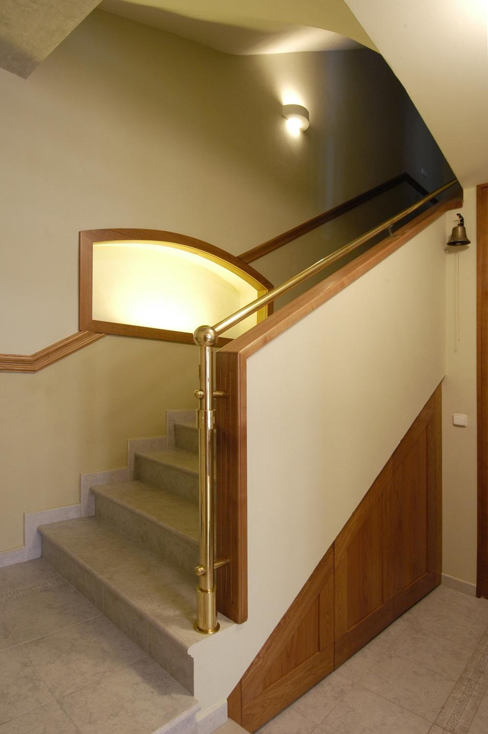 Een houten trap met een leuning en een lamp erboven.