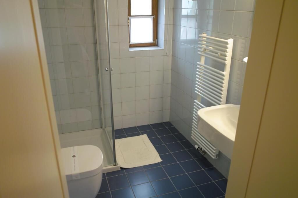 Un baño pequeño con inodoro, ducha y lavamanos.