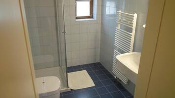 Un baño pequeño con inodoro, ducha y lavamanos.