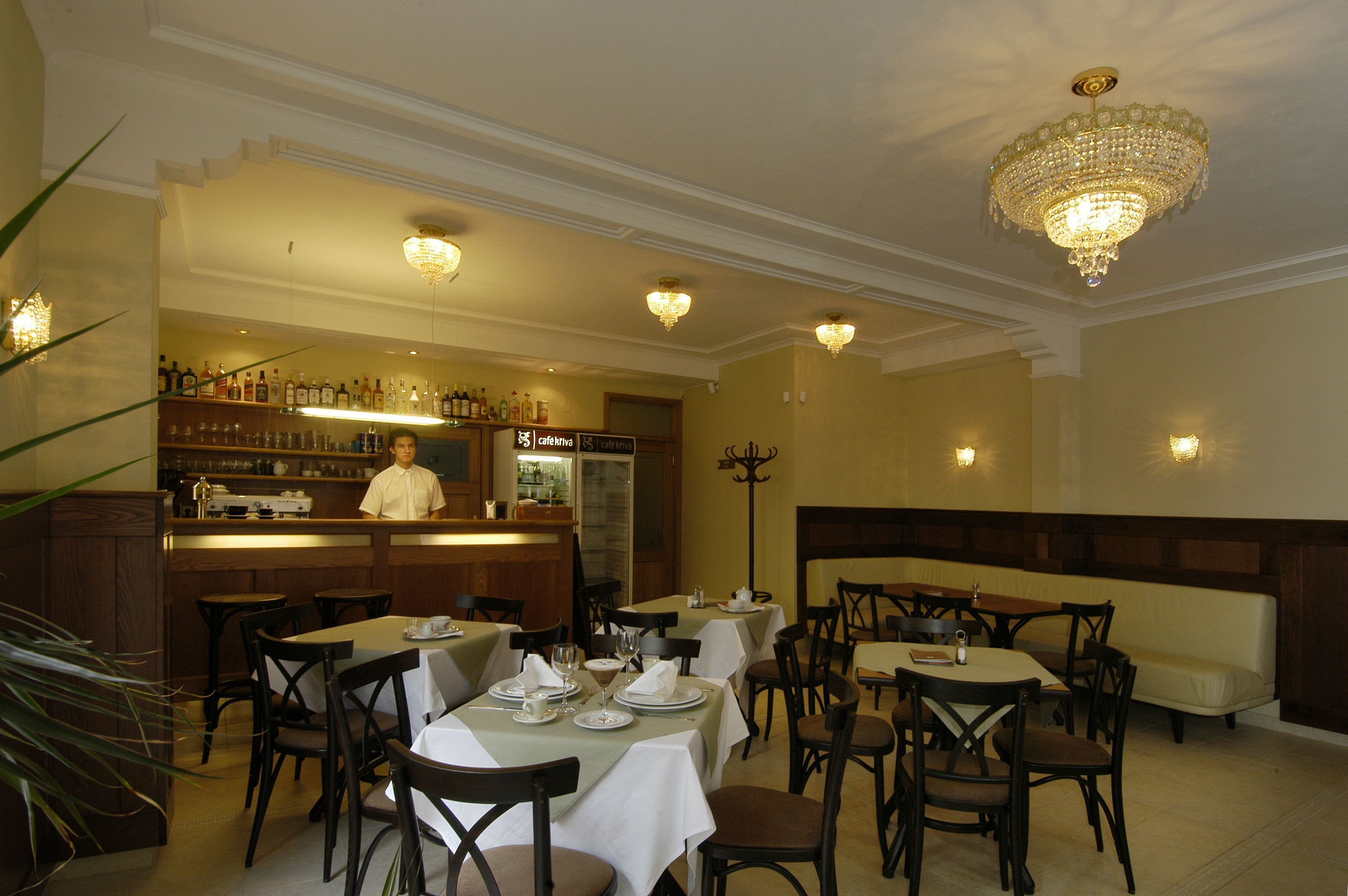 Un restaurante con varias mesas y sillas, una zona de bar y un candelabro.