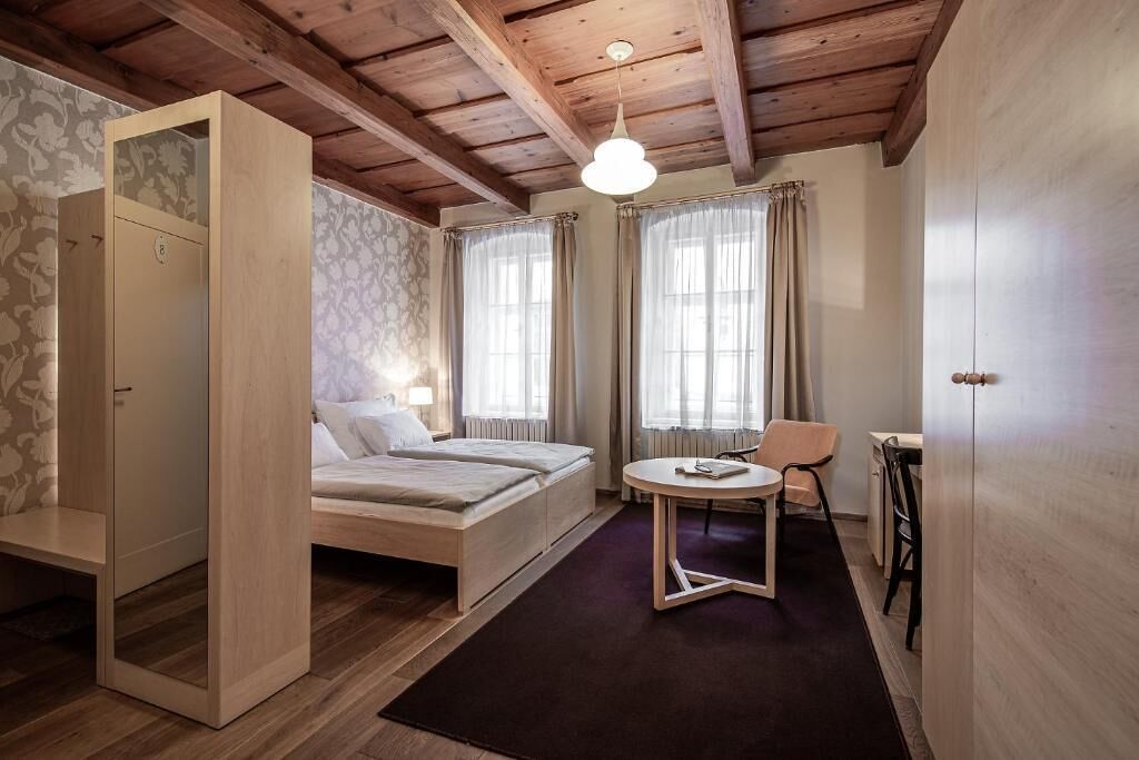 A room with a bed, a small table, a chair, and a wardrobe.