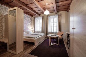 A room with a bed, a small table, a chair, and a wardrobe. - Pension Krivá (Olomouc)