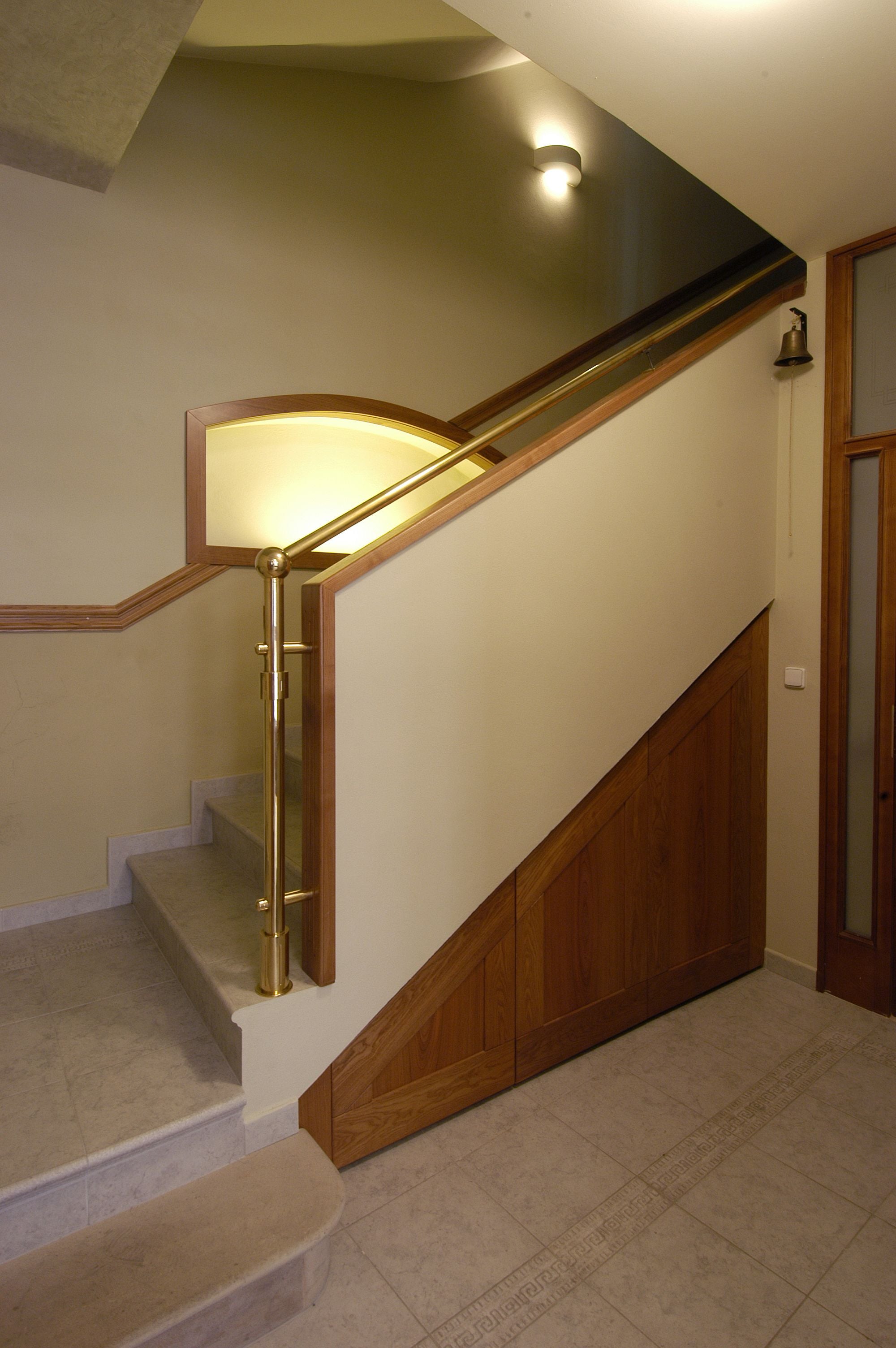 Un escalier avec une rampe en bois et un luminaire placé au-dessus.