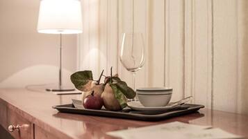 A wooden table with a glass, a bowl, and a plate with fruits and a napkin.