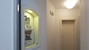 A hallway with a statue in a glass case, a door with a number, and a ceiling light. - Pension Krivá (Olomouc)