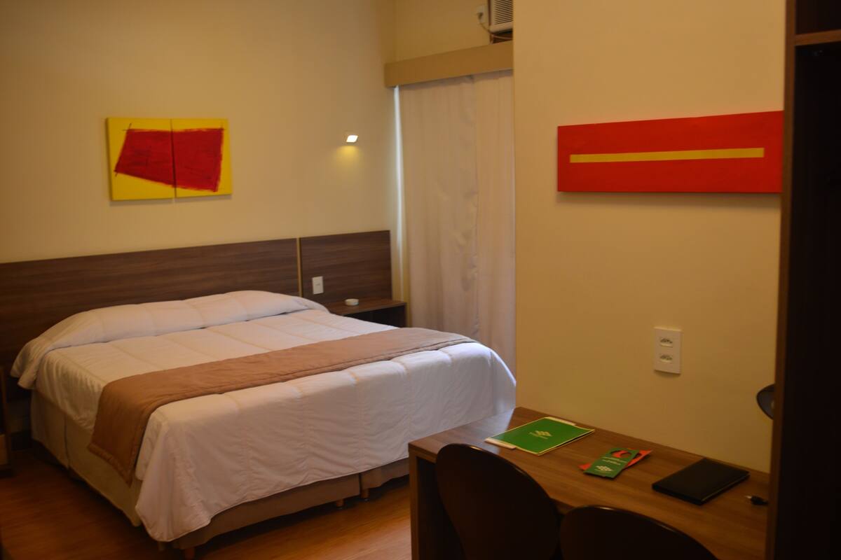 Ein Hotelzimmer mit einem Bett, einem Schreibtisch und zwei Bildern an den Wänden.