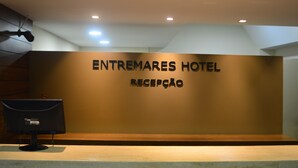 A reception area with a sign reading "ENTREMARES HOTEL RECEPCAO" and a computer monitor on a counter. - Entremares Hotel (Rio de Janeiro)