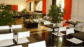 A modern hotel lobby with a spacious layout, featuring a central seating area with a sofa and chairs, surrounded by tables and chairs. - Entremares Hotel (Rio de Janeiro)