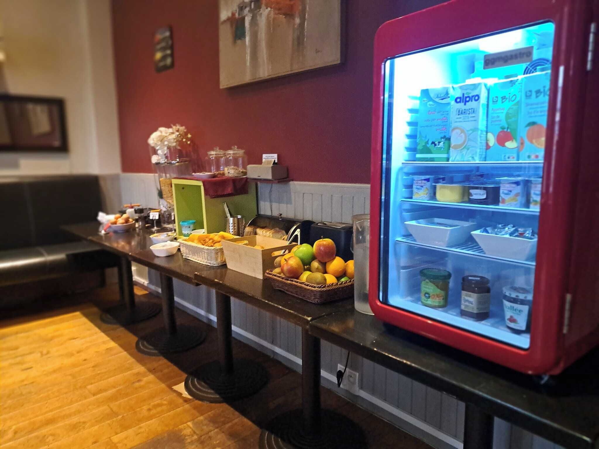 Een ontbijtbalk met een koelkast vol drankjes en een fruitmand.