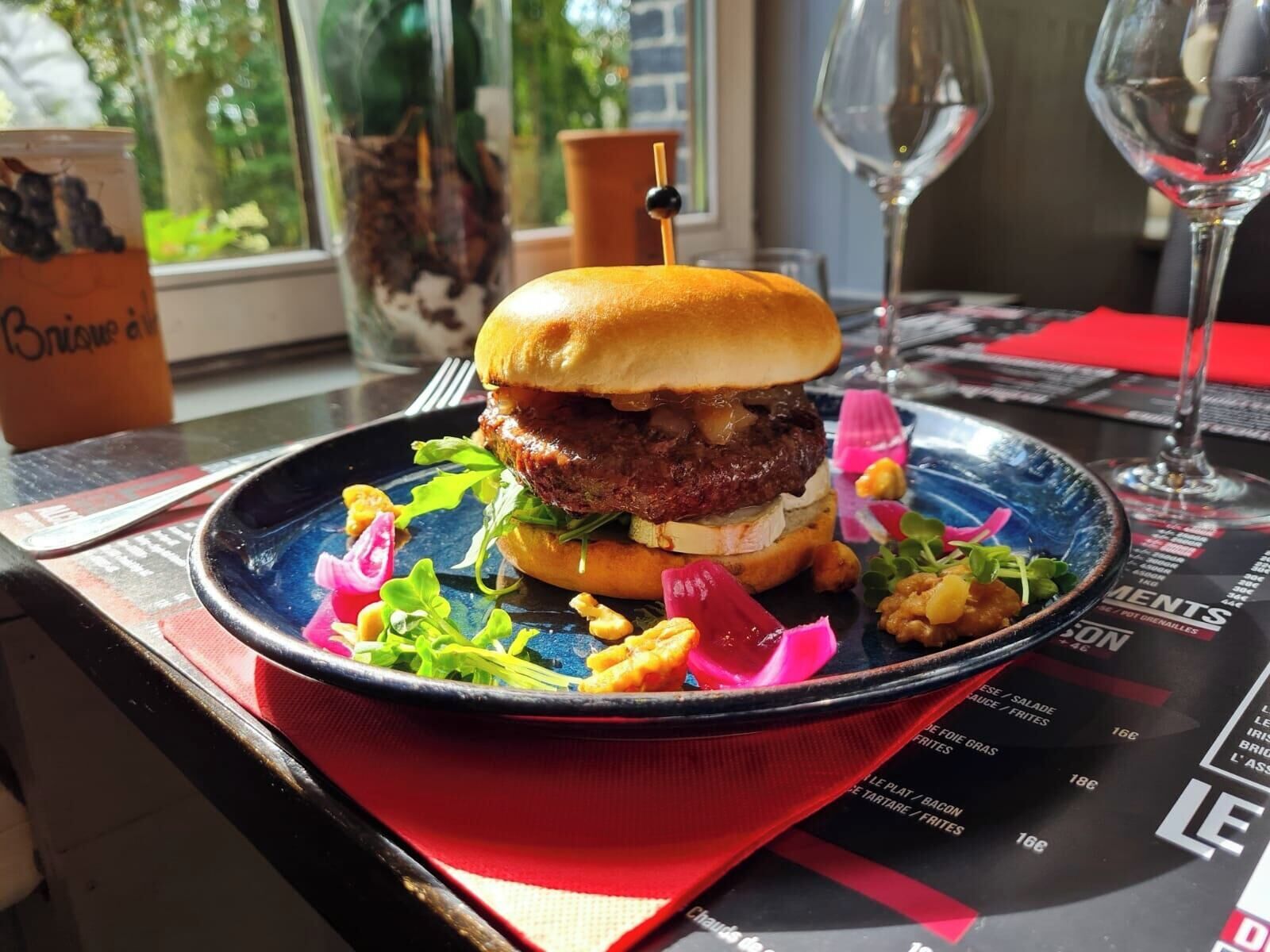 Een hamburger met broodje, sla en een portie friet op een blauw bord.
