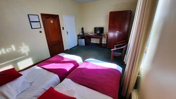 Een hotelkamer met twee bedden, een bureau, een televisie en een deur.