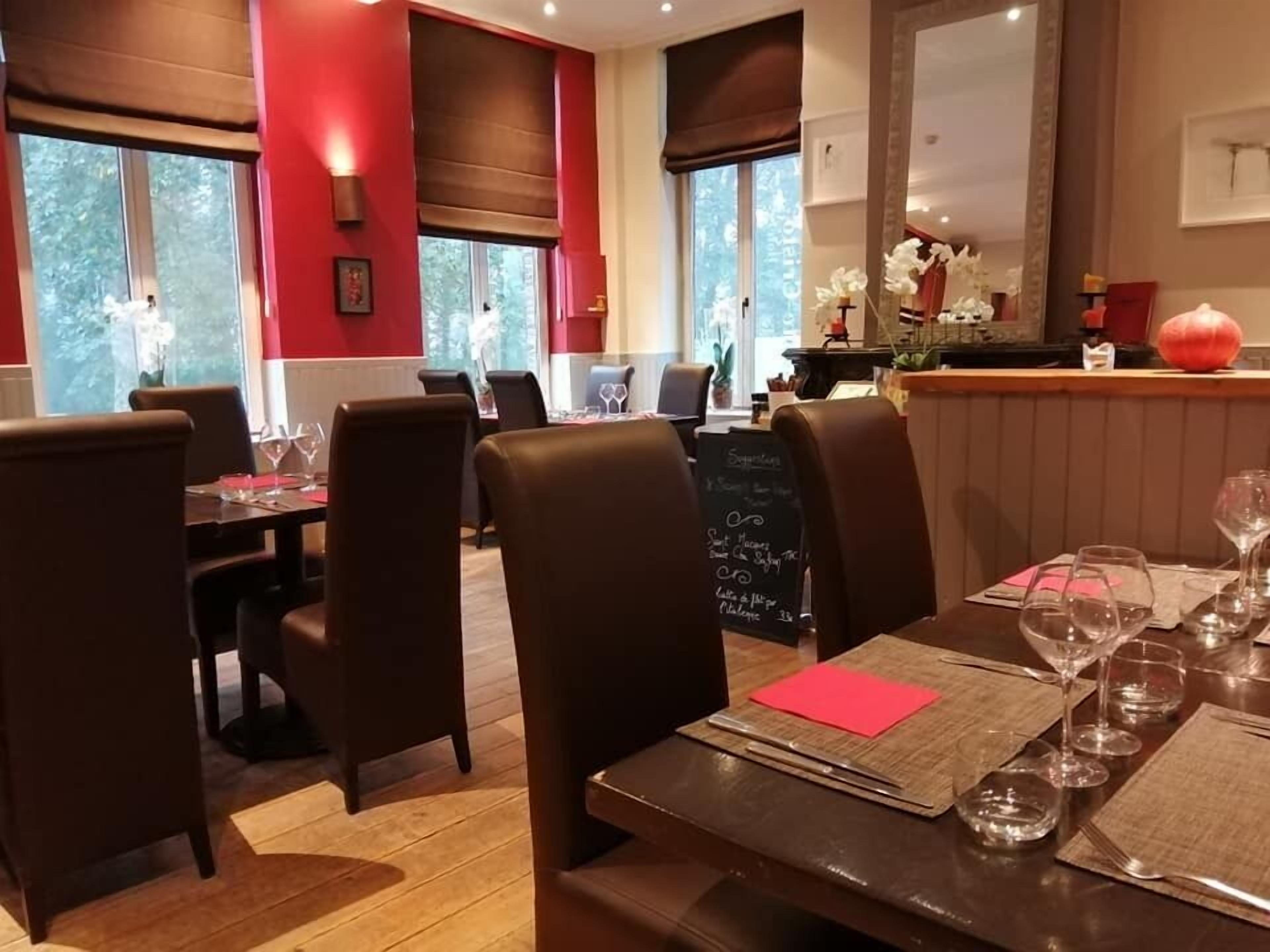 A restaurant with wooden tables and chairs, a chalkboard menu, and large windows with curtains.