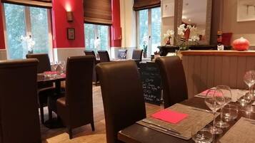 A restaurant with wooden tables and chairs, a chalkboard menu, and large windows with curtains.