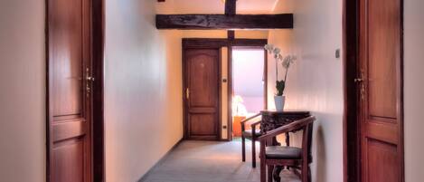 Un pasillo con puertas de madera, una silla de madera oscura y una orquídea en maceta.