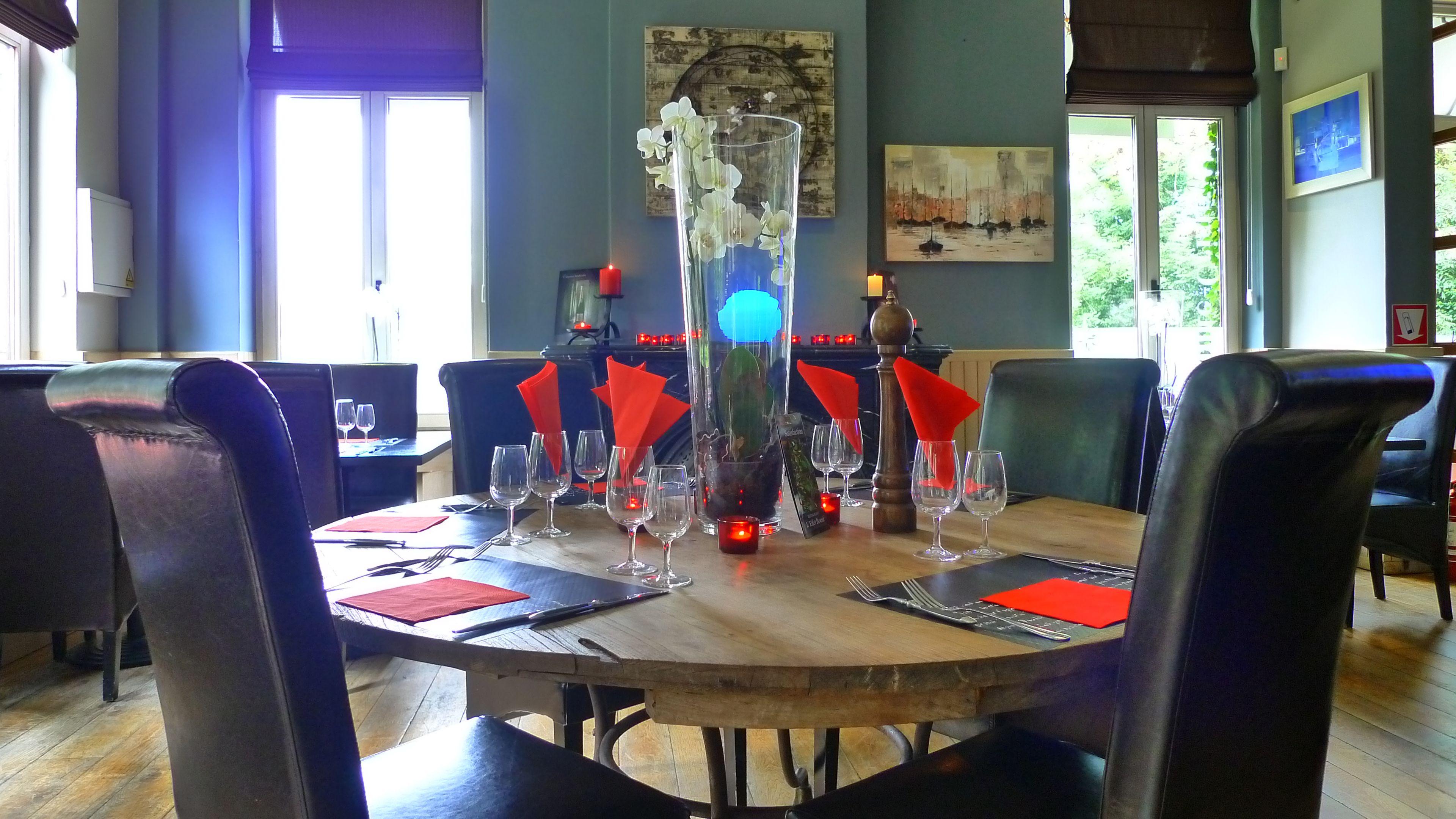A dining area with a wooden table set for a meal, surrounded by chairs.