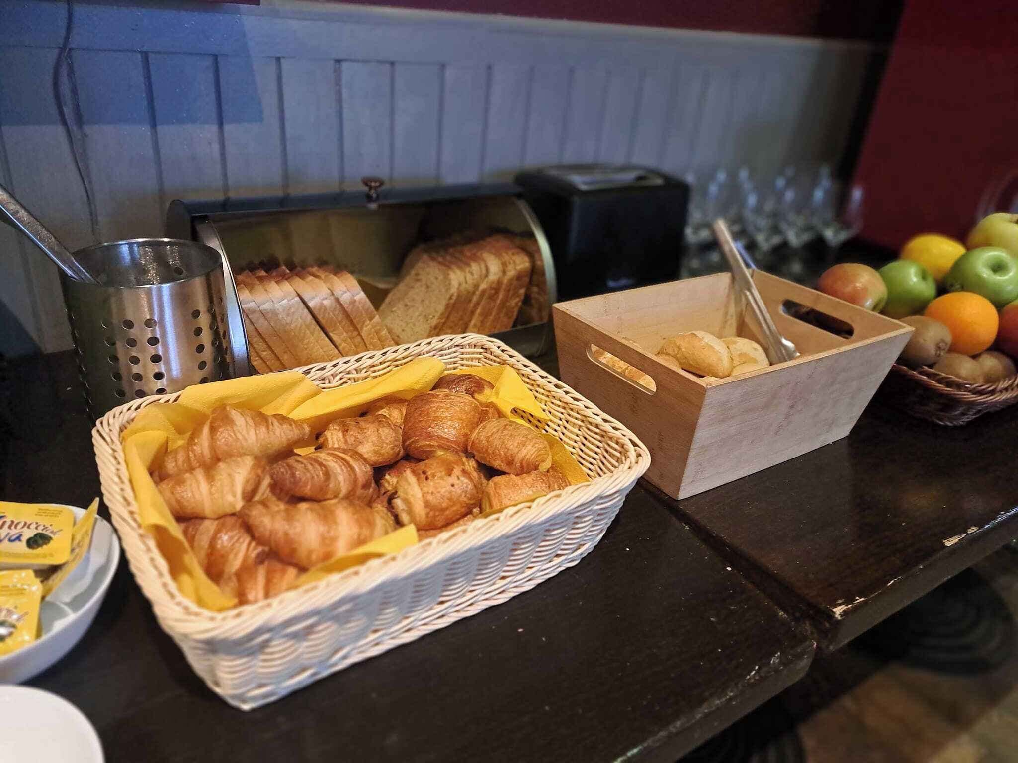 Un bufé de desayuno con croissants, pan y frutas.