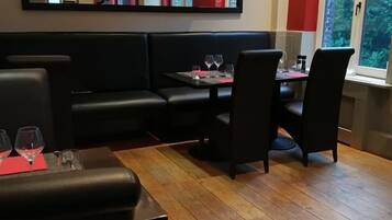 A cozy dining area with a 'HOME' sign, wooden flooring, black leather seating, and a window with a view.