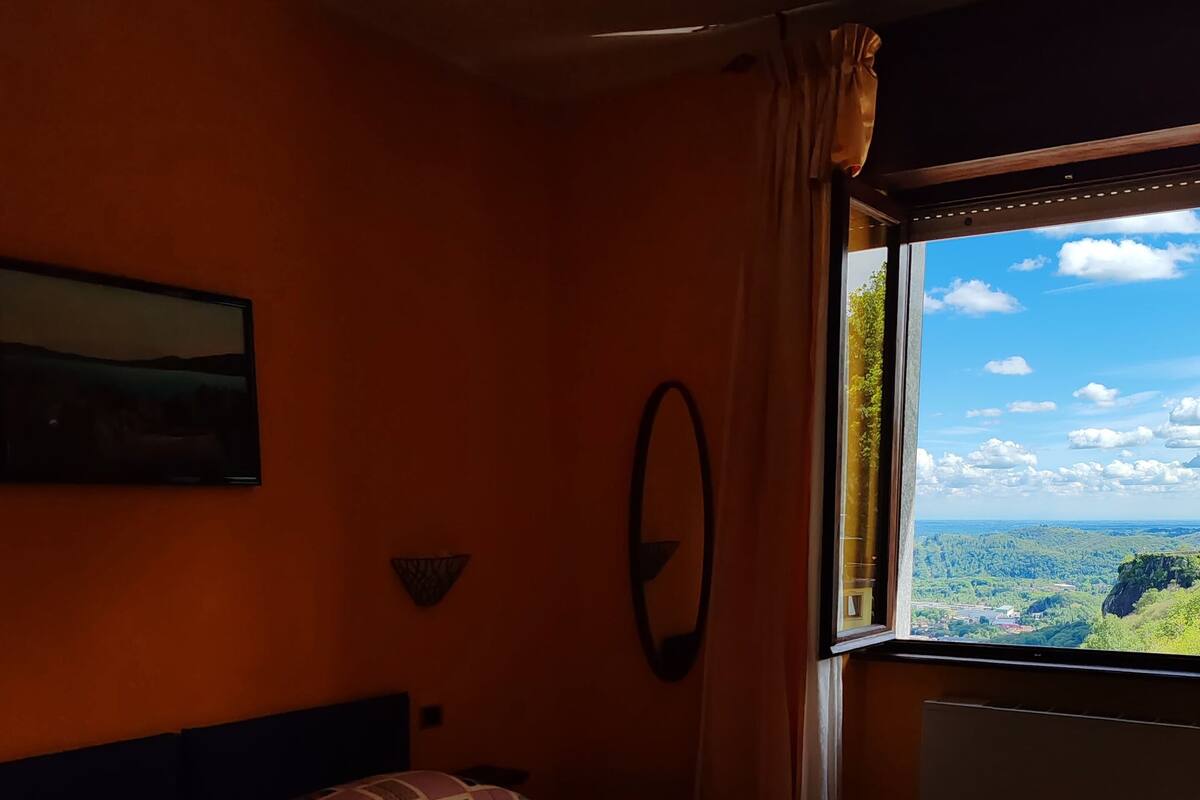 Ein Schlafzimmer mit Bett, einem Fenster mit Landschaftsblick und einem Bild an der Wand.
