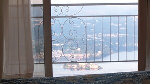 A room with a view of a lake and a distant town through a metal railing. - Hotel Panoramico lago d'Orta adults only (Madonna del Sasso)