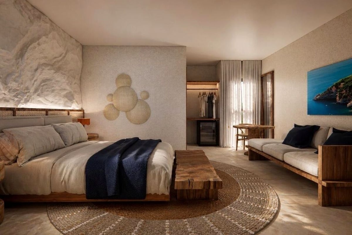 Een moderne slaapkamer met een bed, een houten salontafel, een bank en een schilderij aan de muur.