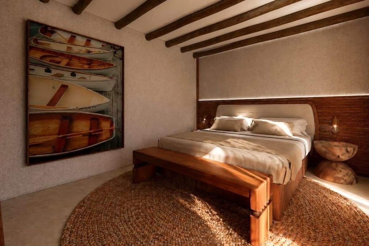 Een slaapkamer met een houten bed, een schilderij van boten aan de muur en een kamerkleed met een structuur.