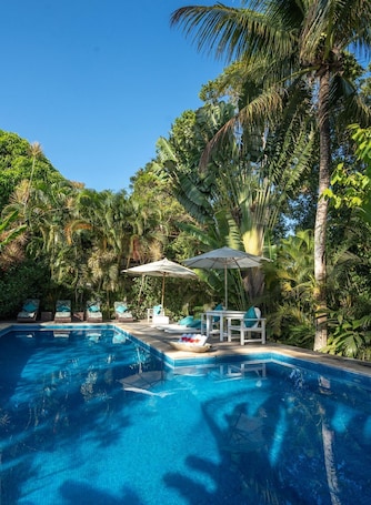 Una piscina al aire libre, sombrillas, sillones reclinables de piscina