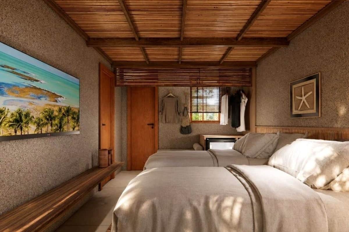 Een slaapkamer met twee bedden, een houten bankje, een schilderij van een strand en een zeester decoratie.