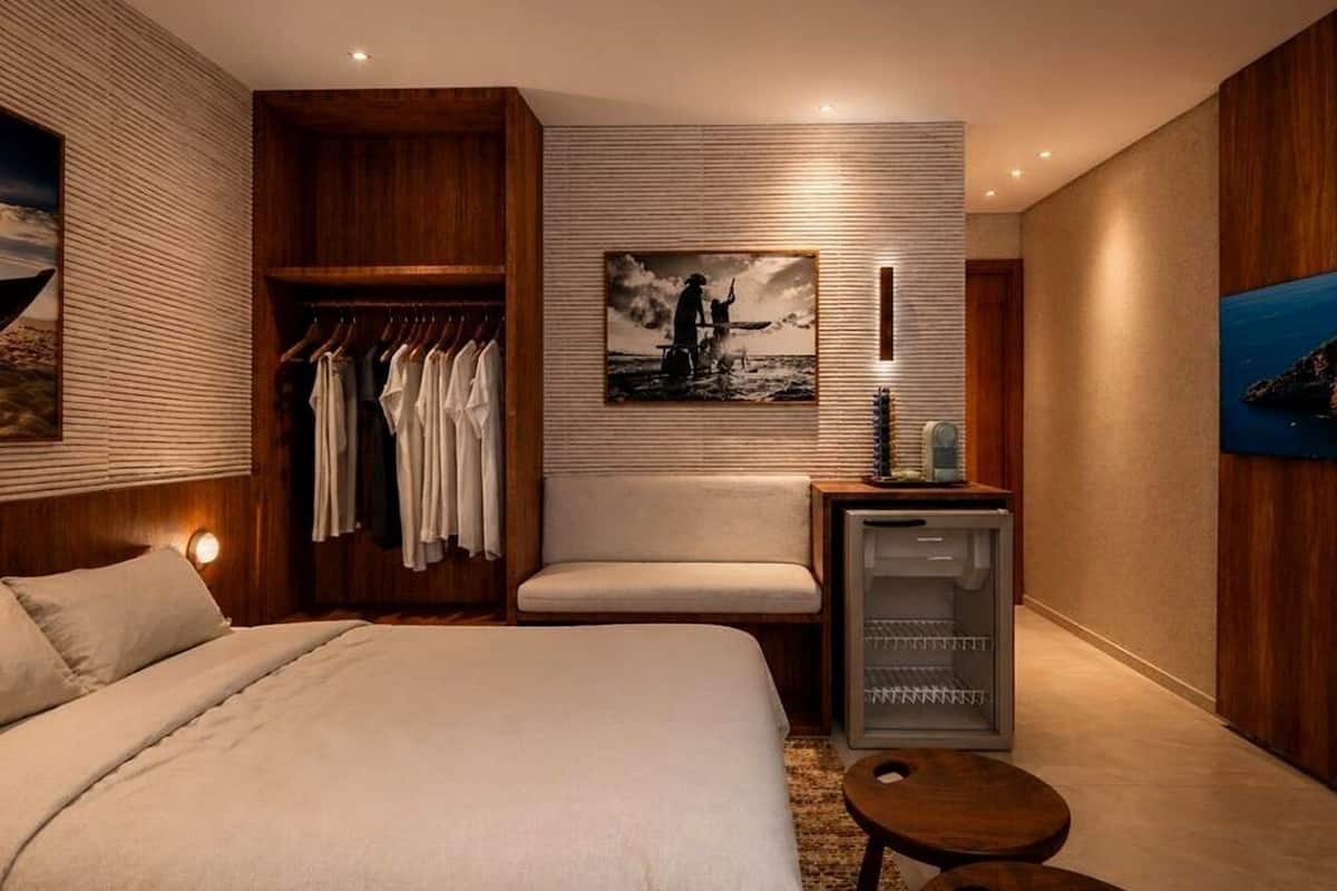 Een slaapkamer met een bed, een zithoek, een kledingkast en een kleine tafel.