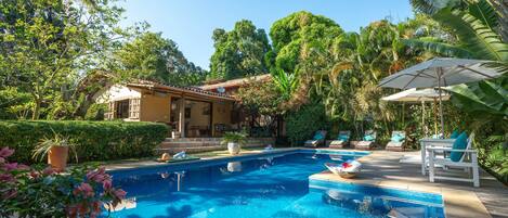 Una piscina al aire libre, sombrillas, tumbonas