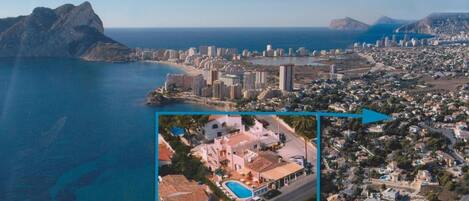 An aerial view of a coastal city with a prominent beach, high-rise buildings, and a residential area.