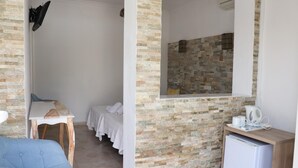 A compact room with a bed, a small table, a mirror, and a mini-fridge. - Hostal La Paloma I (Calpe)