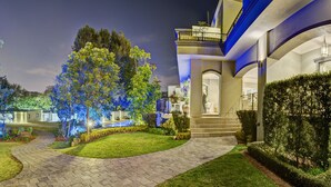 A landscaped garden with illuminated trees and a pathway leading to a building with a balcony. - The Marion on Nicol (Sandton)