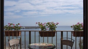 A balcony with wicker chairs, a small table, and potted plants. - Hotel Marinella (Marciana Marina)