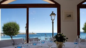 A dining table set for six with a view of the sea and a lamp post. - Hotel Marinella (Marciana Marina)