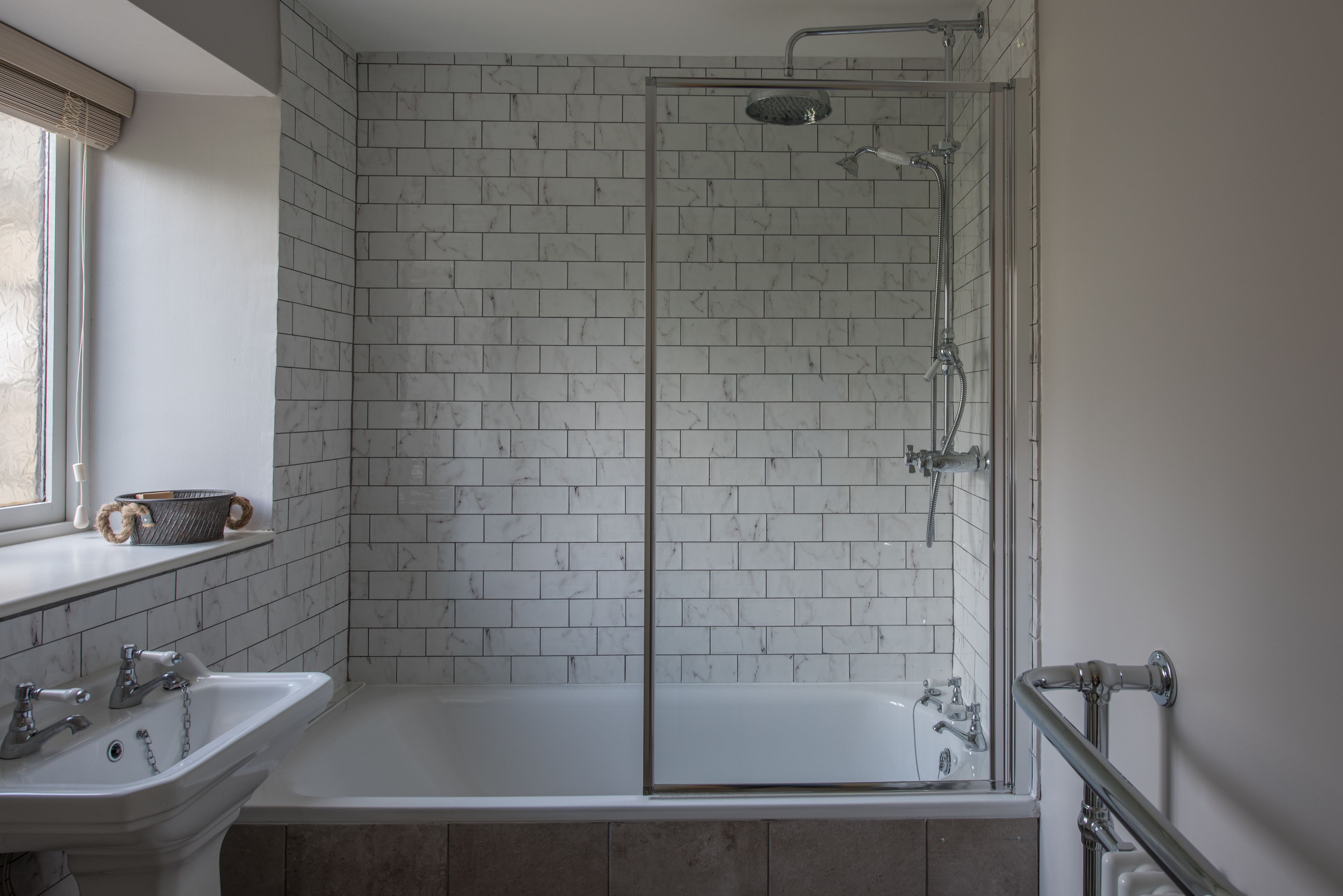 Un baño con ducha de vidrio, lavamanos blanco y bañera.