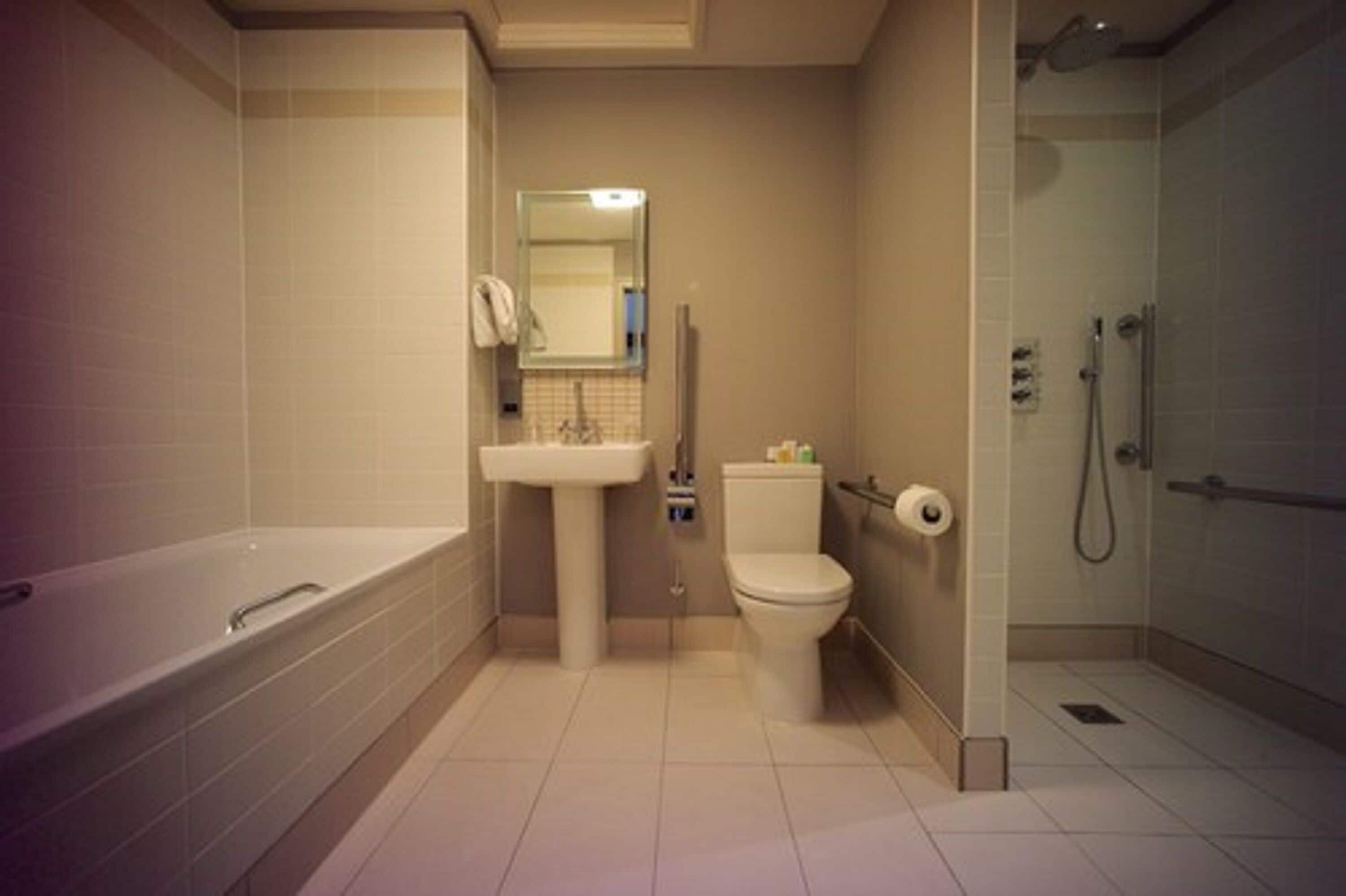 A modern bathroom with a bathtub, sink, toilet, and shower.