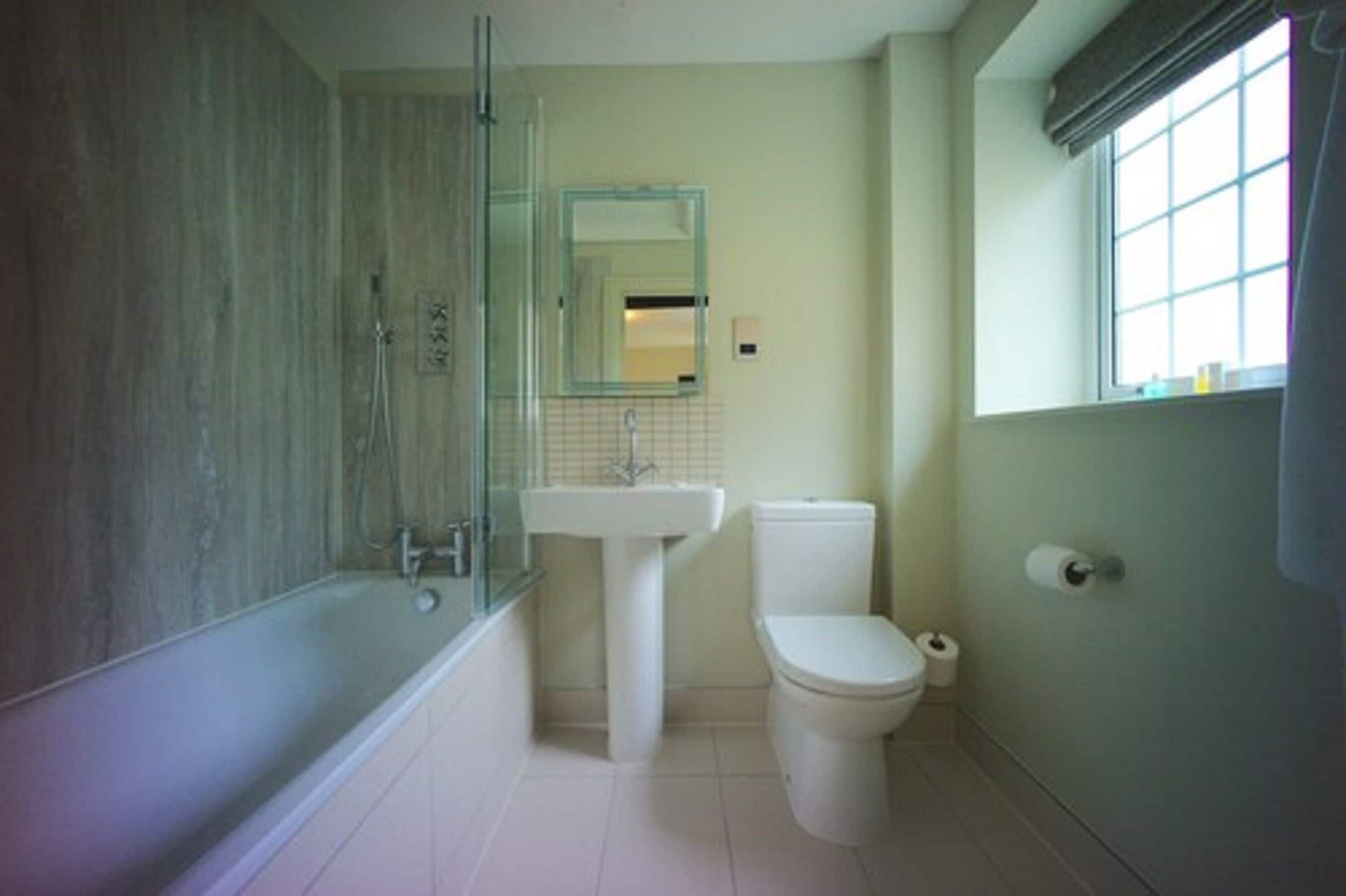 Baño con bañera, lavamanos, inodoro y ventana.