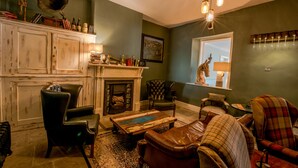 Una sala de estar acogedora con chimenea, muebles de cuero y vistas a la ciudad desde una ventana.
