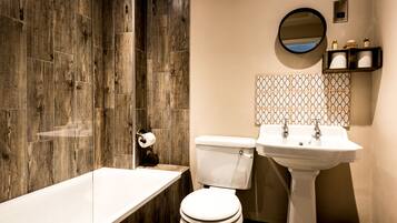 Ein Badezimmer mit Holzduschwand, Toilette, Waschbecken und Spiegel.