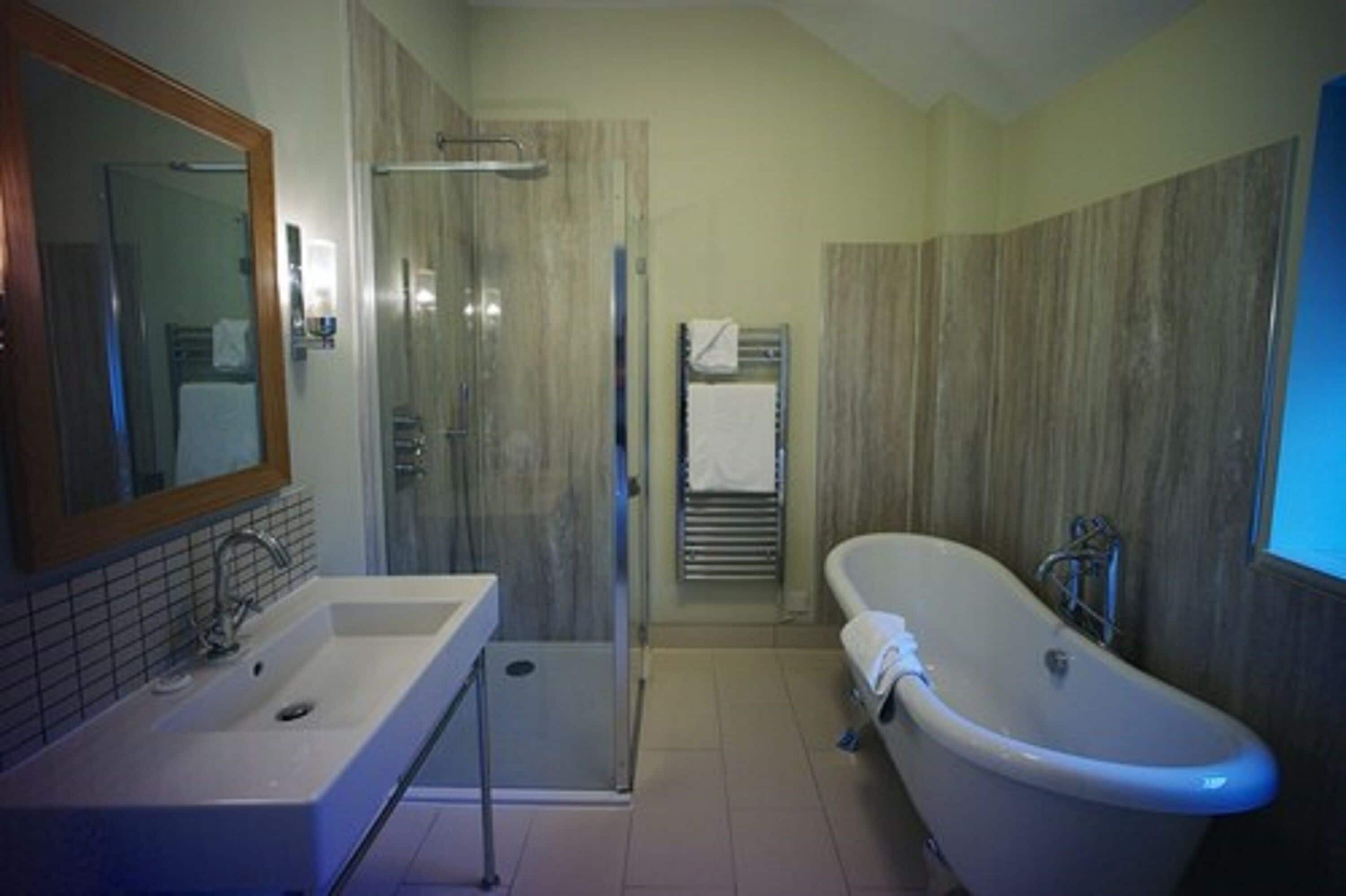 Een badkamer met wastafel, spiegel, douche en bad.