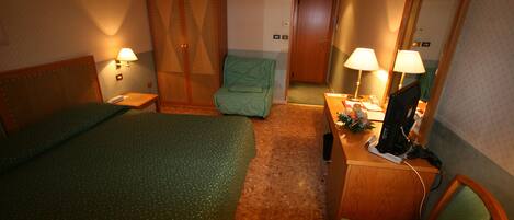 A hotel room with two beds, a desk with a computer, a chair, a wardrobe, and two wall lamps.