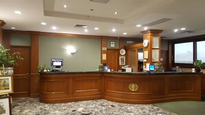 Un área de recepción con un mostrador de madera, un monitor de computadora, un reloj y certificados enmarcados en la pared.