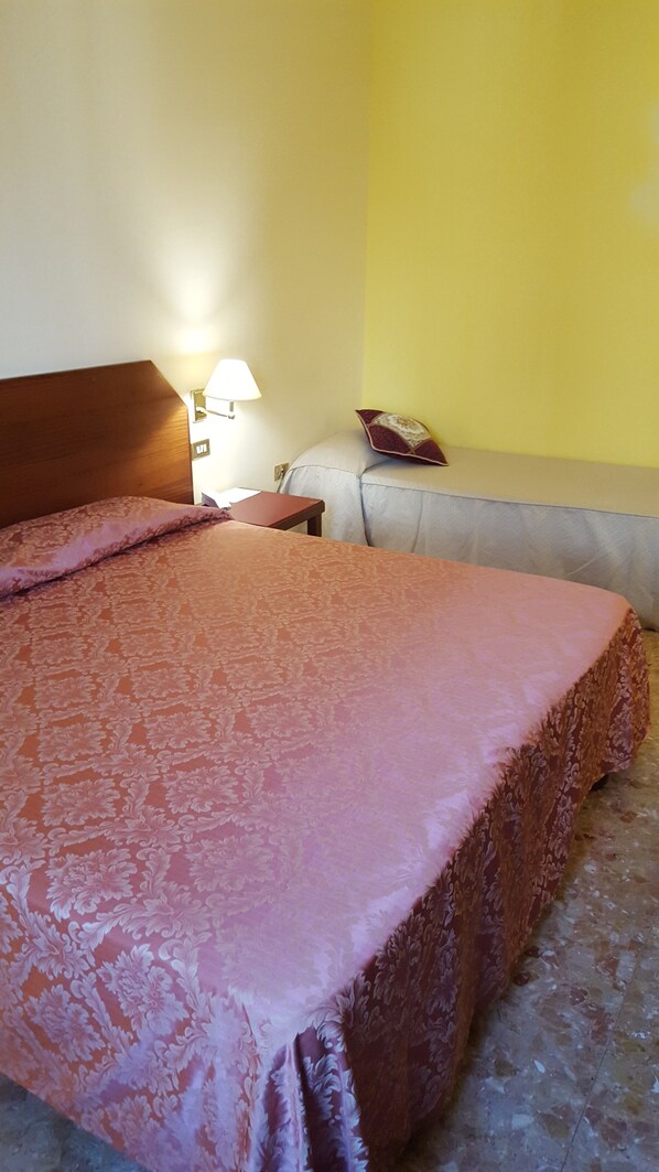 A hotel room with a large bed, a nightstand, a lamp, and a sofa. - Nuovo Albergo (Chieti)
