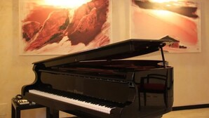 A grand piano in a room with two large landscape paintings on the wall. - Hotel Miletto (San Massimo)