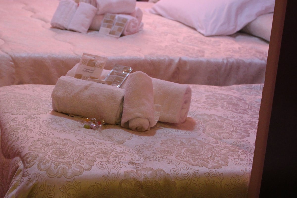 Two beds with neatly folded towels and toiletries.