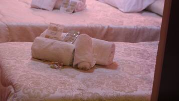 Deux lits avec des serviettes soigneusement pliées et des articles de toilette.