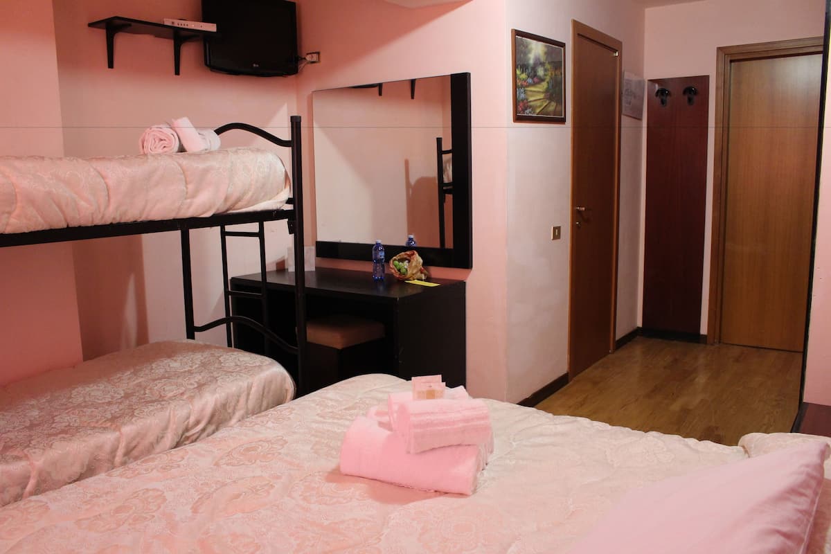A bedroom with two beds, a desk, a mirror, and a wardrobe.