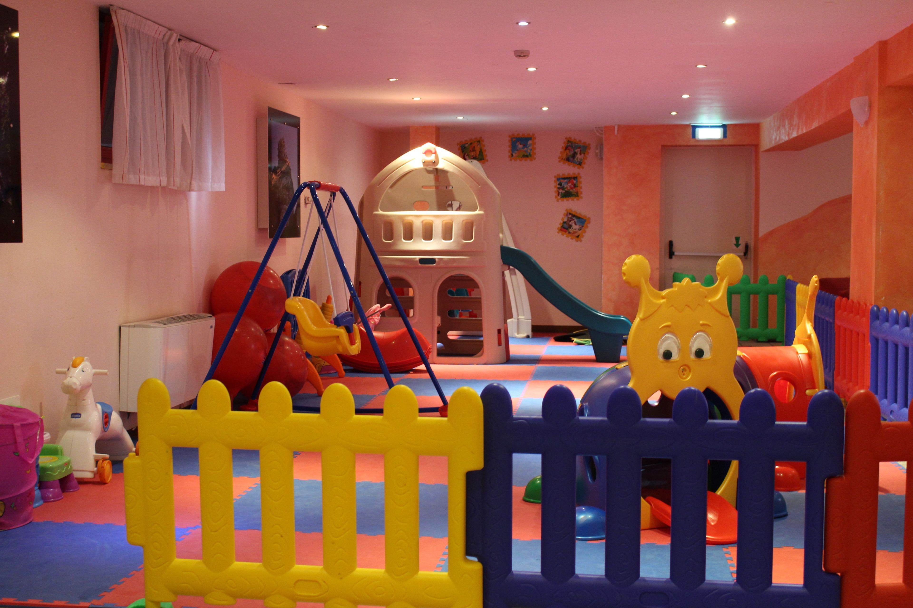 A children's play area with a slide, swing set, and soft play structures.